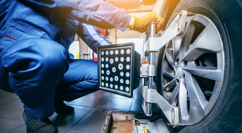 A technician installing the wheel alignment equipment on a tire.