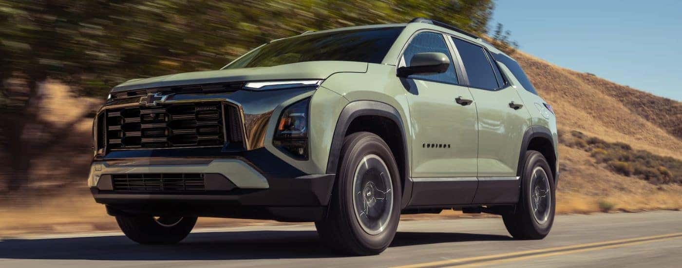 Green 2026 Chevy Equinox LT driving on a paved road.