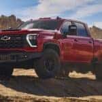 A red 2026 Chevy Silverado 2500 HD ZR2 Bison Edition shown parked on rocky terrain.