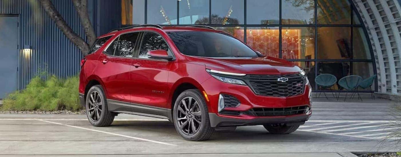 A red 2024 Chevy Equinox parked near a hngar.