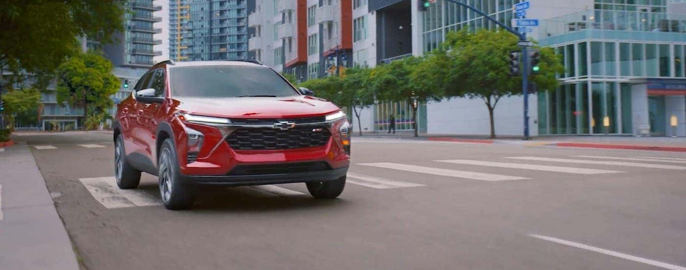 A red 2026 Chevy Trax driving in a city.