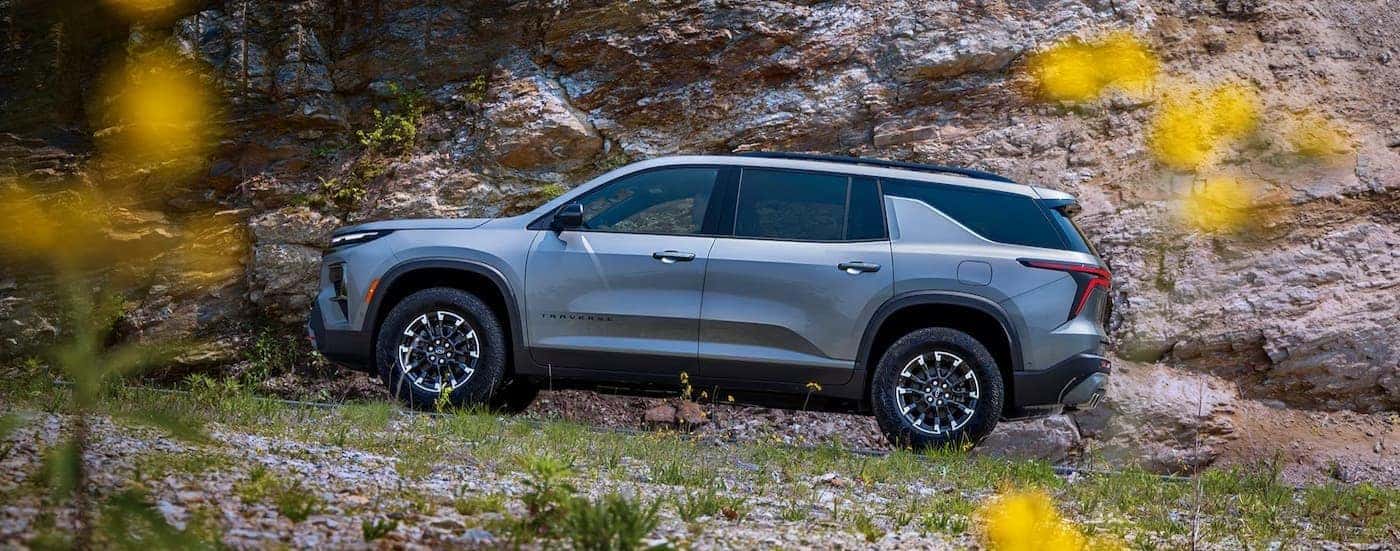 A silver 2026 Chevy Traverse driving uphill.