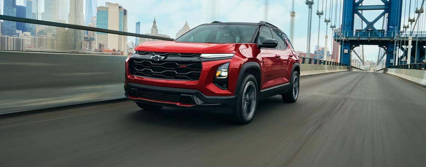A red 2027 Chevy Equinox driving on a bridge