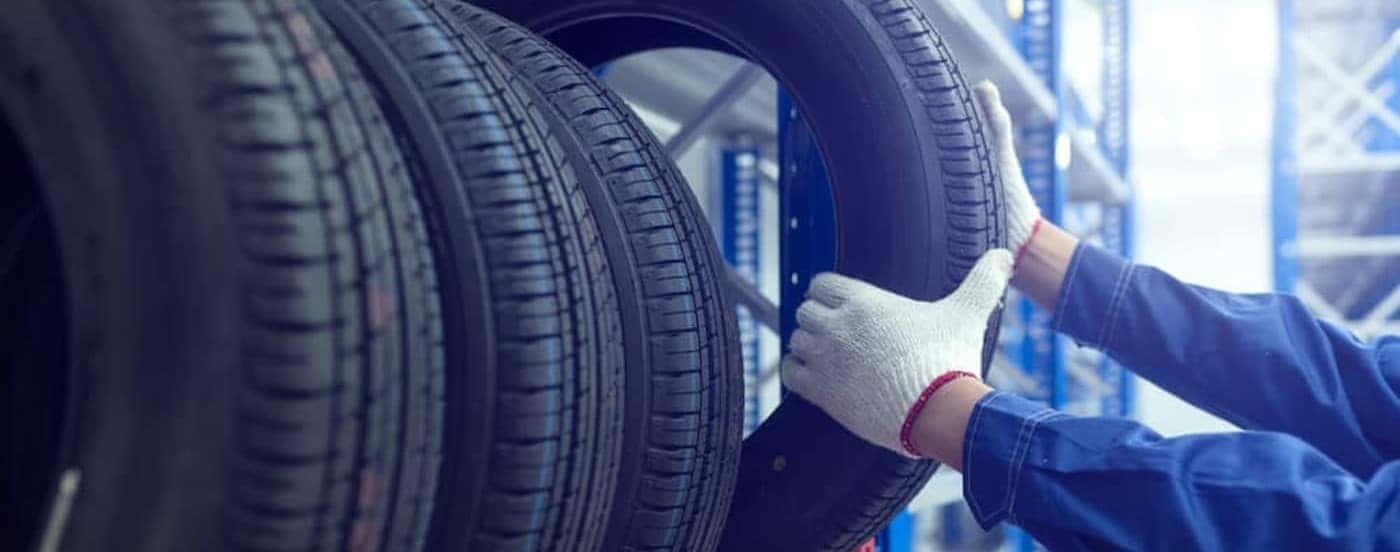 A technician taking a tire off of a rack.