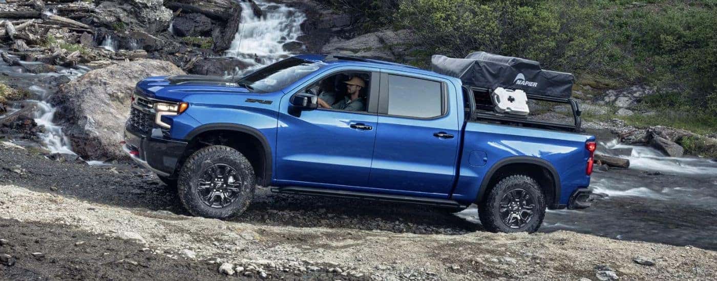 A blue 2024 Chevy Silverado 1500 ZR2 off-roading through a stream