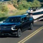A black 2027 Chevy Silverado 1500 High Country towing a boat