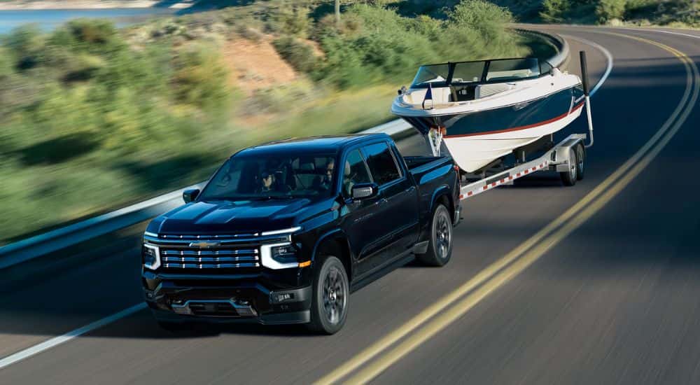A black 2027 Chevy Silverado 1500 High Country towing a boat