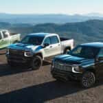 Three green, white and black 2027 Chevy Silverado trucks parked off-road