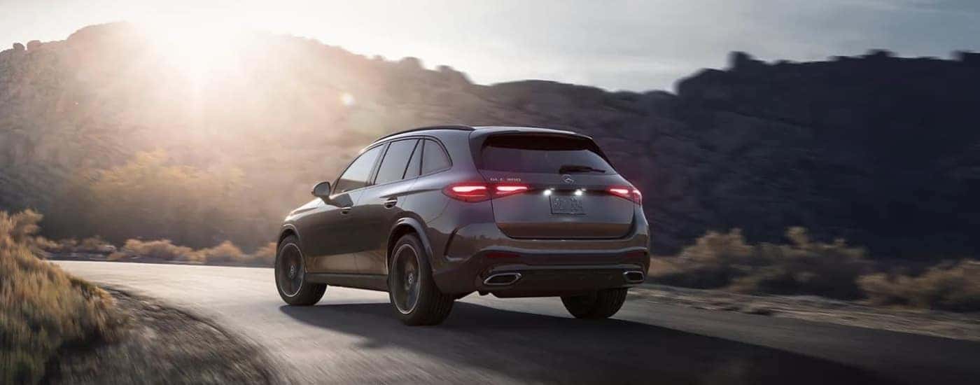 Grey 2023 Mercedes Benz GLC driving down a road at sunset