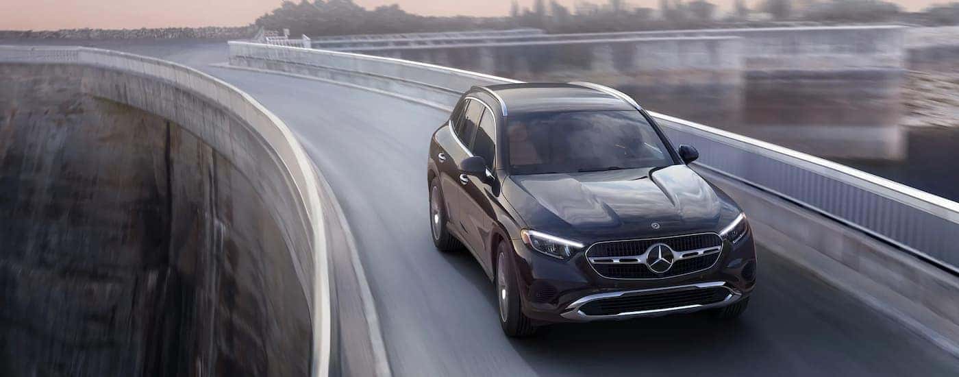 Black 2026 Mercedes-Benz GLC driving across a bridge.