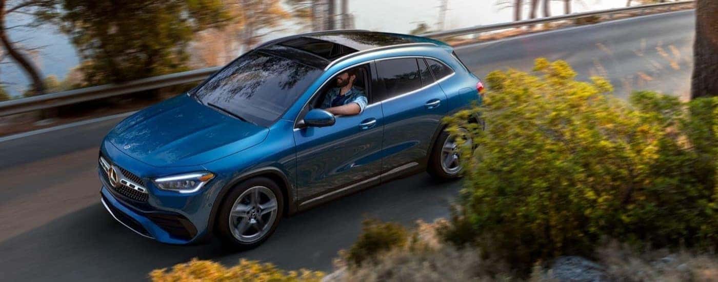 Blue 2023 Mercedes-Benz GLA 250 SUV driving near a lake
