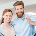 Red haired couple holding car keys and shopping for a used or certified pre-owned vehicle
