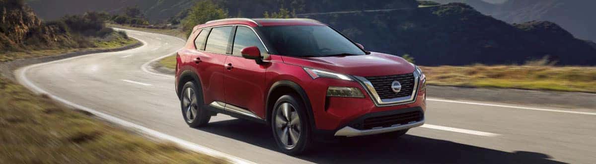 Red Nissan Rogue Driving Down Road