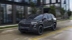 black 2025 chevy equinox driving down a city road