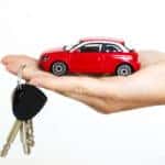 small red car inside someone's hand with keys around finger