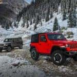Red Jeep Wrangler and Black Jeep Wrangler on Snowy Mountainside
