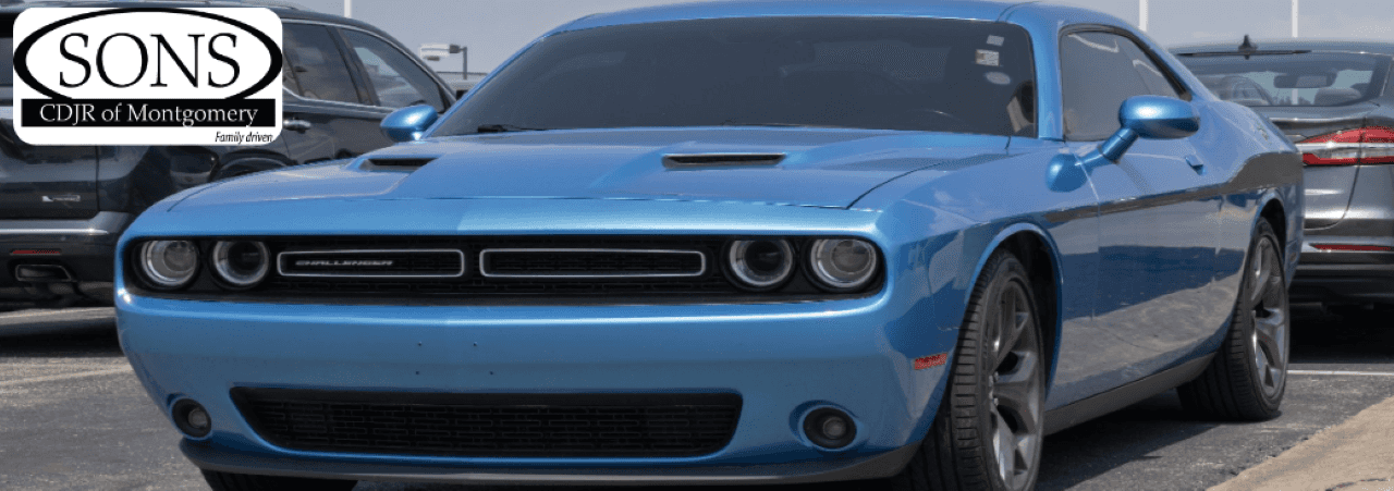 A photo of a blue Dodge Challenger parked at a dealership portraying the diverse inventory of cars, trucks, and SUVs at SONS CDJR Fiat in Montgomery, AL.