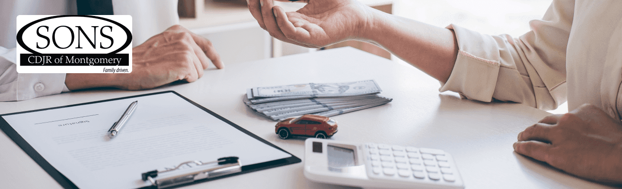 The customer reviews Jeep Wrangler financing options with a representative at SONS CDJR of Montgomery near Prattville, AL.