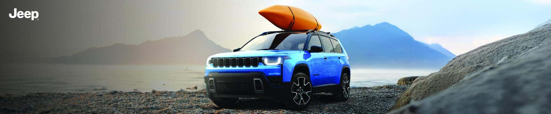 Front three-quarter view of a 2026 Jeep Cherokee Limited in Hydro Blue Pearl parked on a rocky shoreline with an orange kayak.