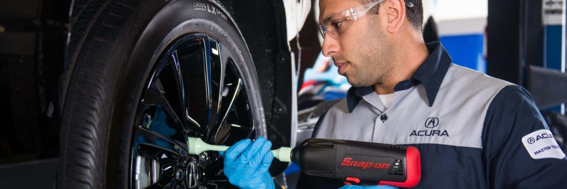acura service technician working on tire