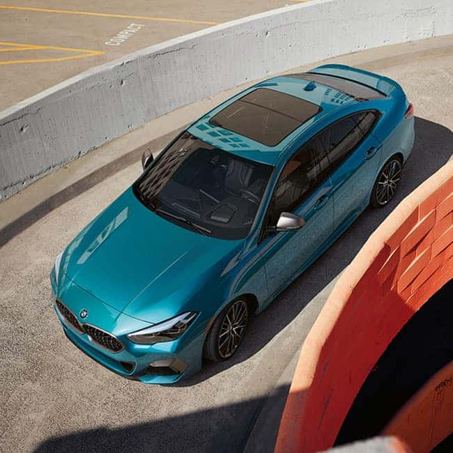 A blue metallic BMW 2 Series Gran Coupe driving down parking garage ramp.