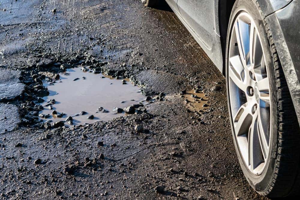 Car next to a pothole in the road