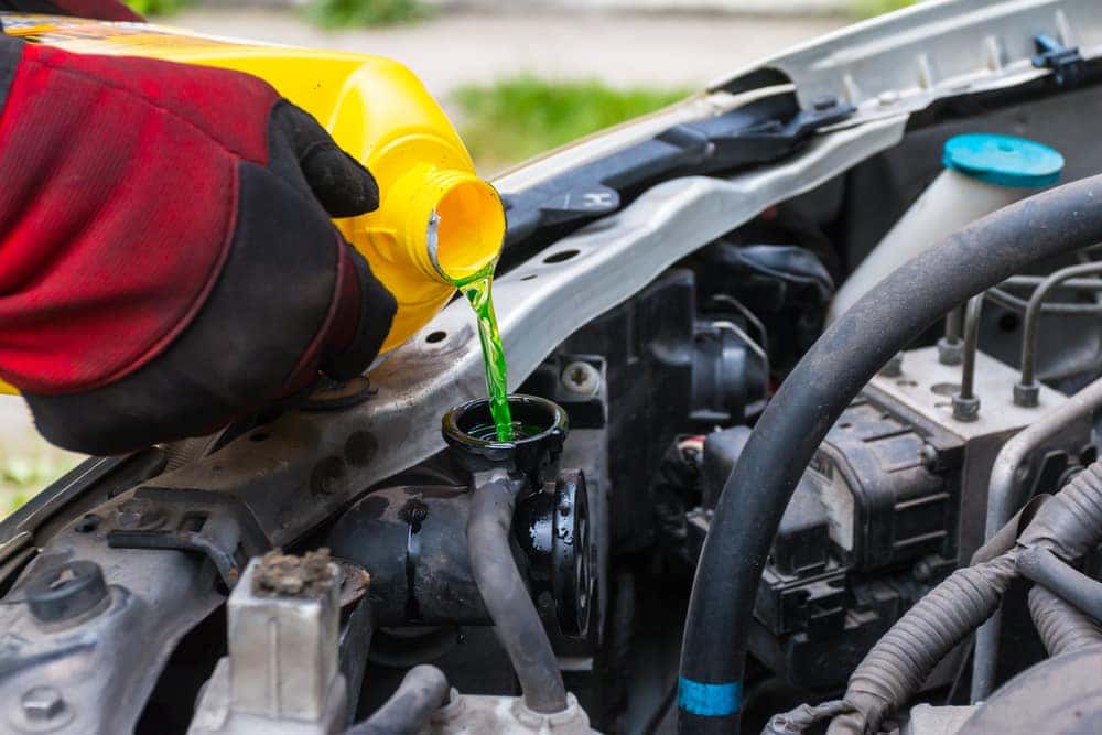 Pouring green coolant into a car engine