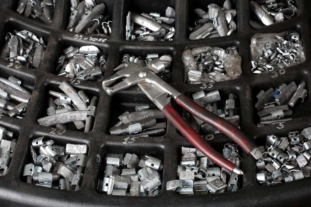 Tray of tire weights with pliers laying on top
