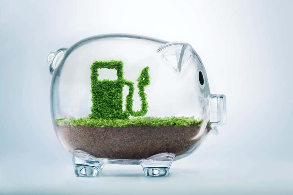 Green gas pump inside of a glass piggy bank