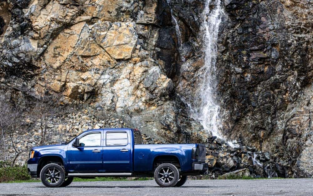 Blue used GMC pickup truck next to a rocky cliff