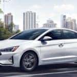 White 2020 Hyundai Elantra driving on highway with city skyline in background