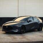 A gray 2025 Mazda3 parked near a warehouse