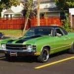 Green 1971 GMC Sprint convertible with black racing stripes in parking spot