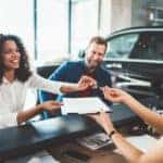 Young woman with her partner signing contract for buying a car