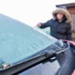 Woman scraping ice from car windscreen