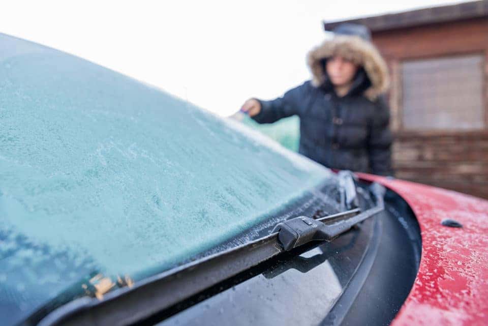 Woman scraping ice from car windscreen
