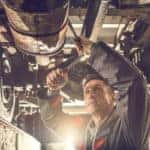 auto mechanic working on a chassis in auto repair shop.