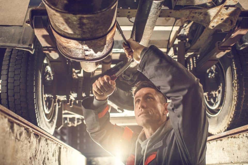 auto mechanic working on a chassis in auto repair shop.